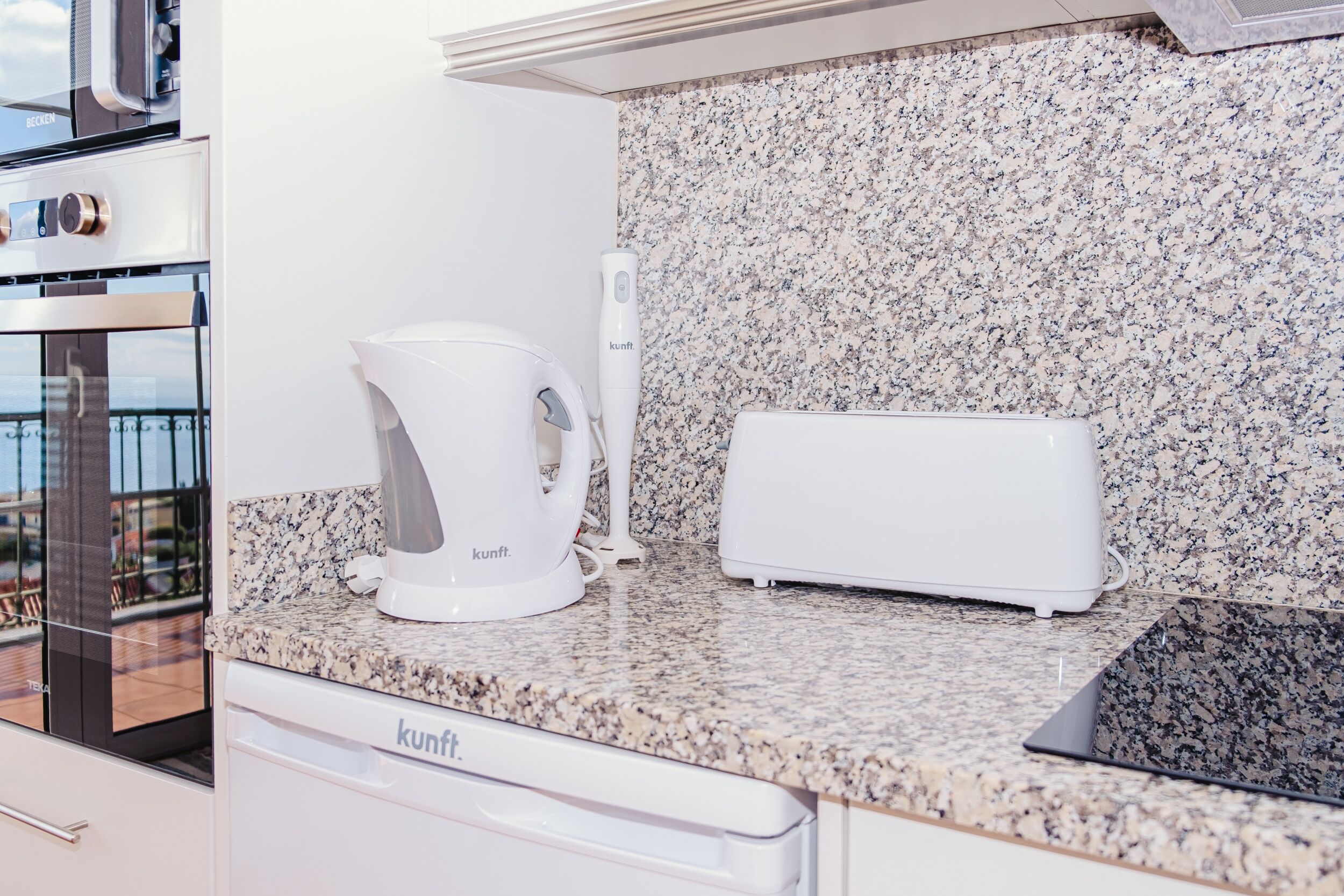 Eine Küche mit Granit Arbeitsplatte, einer Kaffeemaschine, einem Toaster und einem Geschirrspüler.