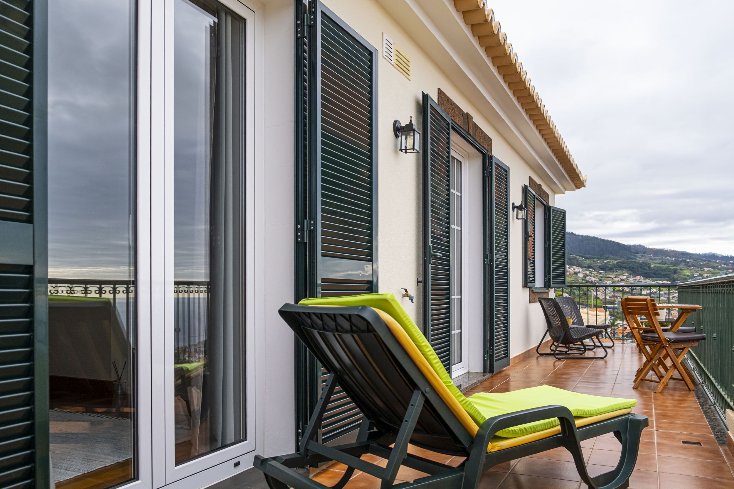 A balcony with two lounge chairs, a table, and a chair.