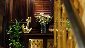 A reception area with a wooden desk, a potted plant, a decorative swan, and a sign indicating the fire exit direction. - Ocean Mist Leith (Edinburgh)