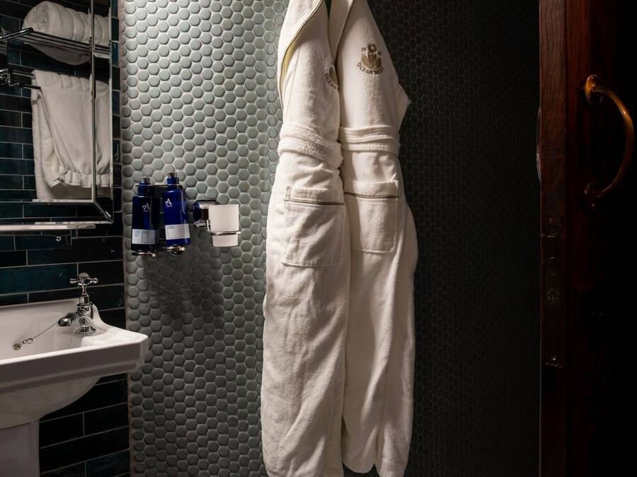 Een badkamer met een ronde spiegel, een wastafel en een handdoekhouder.
