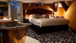 A hotel room with a large bed, a bathtub, and a patterned floor.