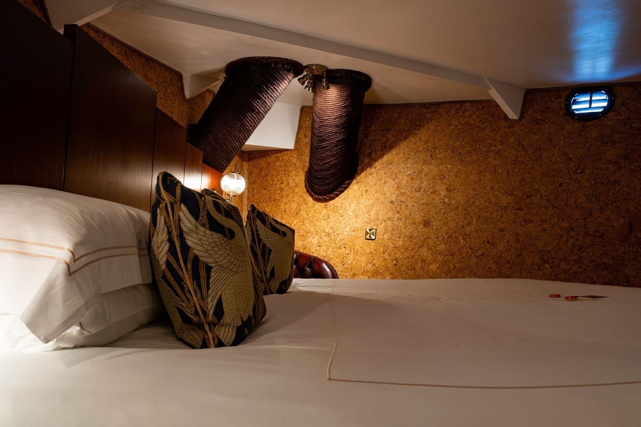 A hotel room with a bed, pillows, a lamp, and a textured wall.