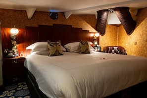 A hotel room with a large bed, wooden headboard, and a nightstand with a lamp and a clock. - Ocean Mist Leith (Edinburgh)