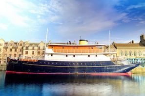 A large ship docked in a harbor with buildings in the background. - Ocean Mist Leith (Edinburgh)