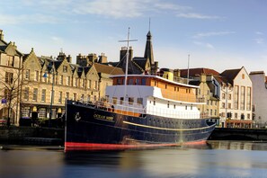 A large boat named 'Ocean Mist' docked at a harbor with historic buildings in the background.