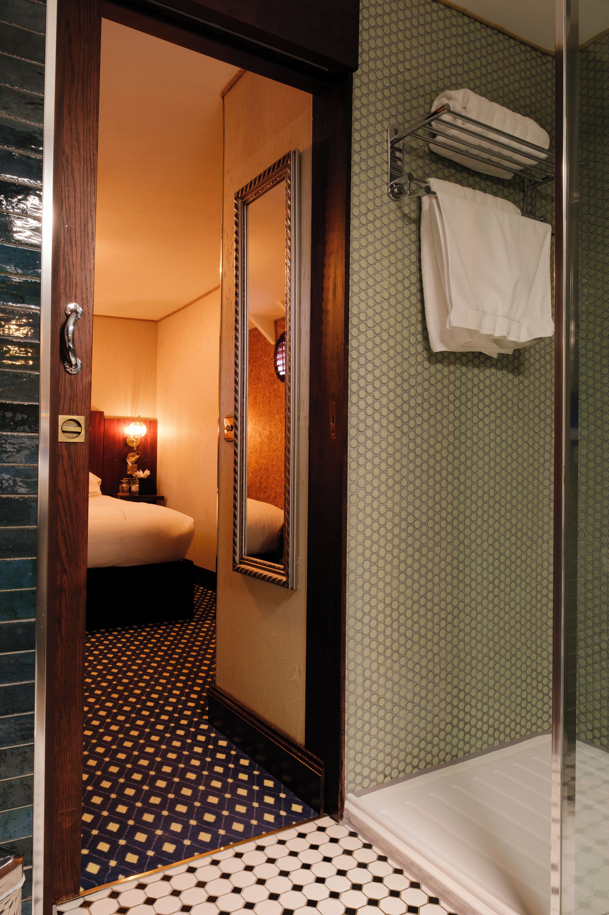 Ein Hotelzimmer mit Bett, Spiegel, Dusche und Handtuchhalter.