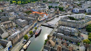 A cityscape with a river, historic buildings, and a mix of residential and commercial structures.