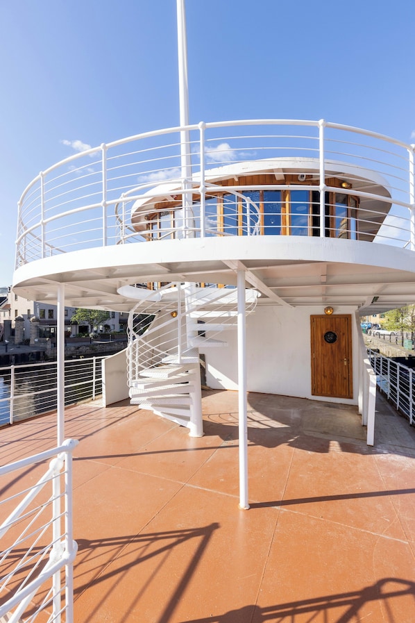 A circular deck with a spiral staircase, a wooden door, and a railing. - Ocean Mist Leith (Edinburgh)