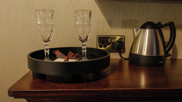 A kitchen counter with a coffee maker, two glasses, and a decorative plate. - Ocean Mist Leith (Edinburgh)