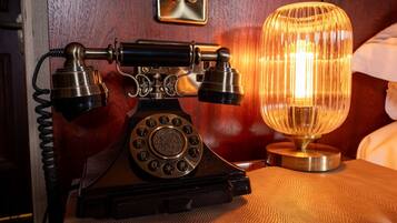 A vintage rotary dial telephone and a glass table lamp on a textured surface.