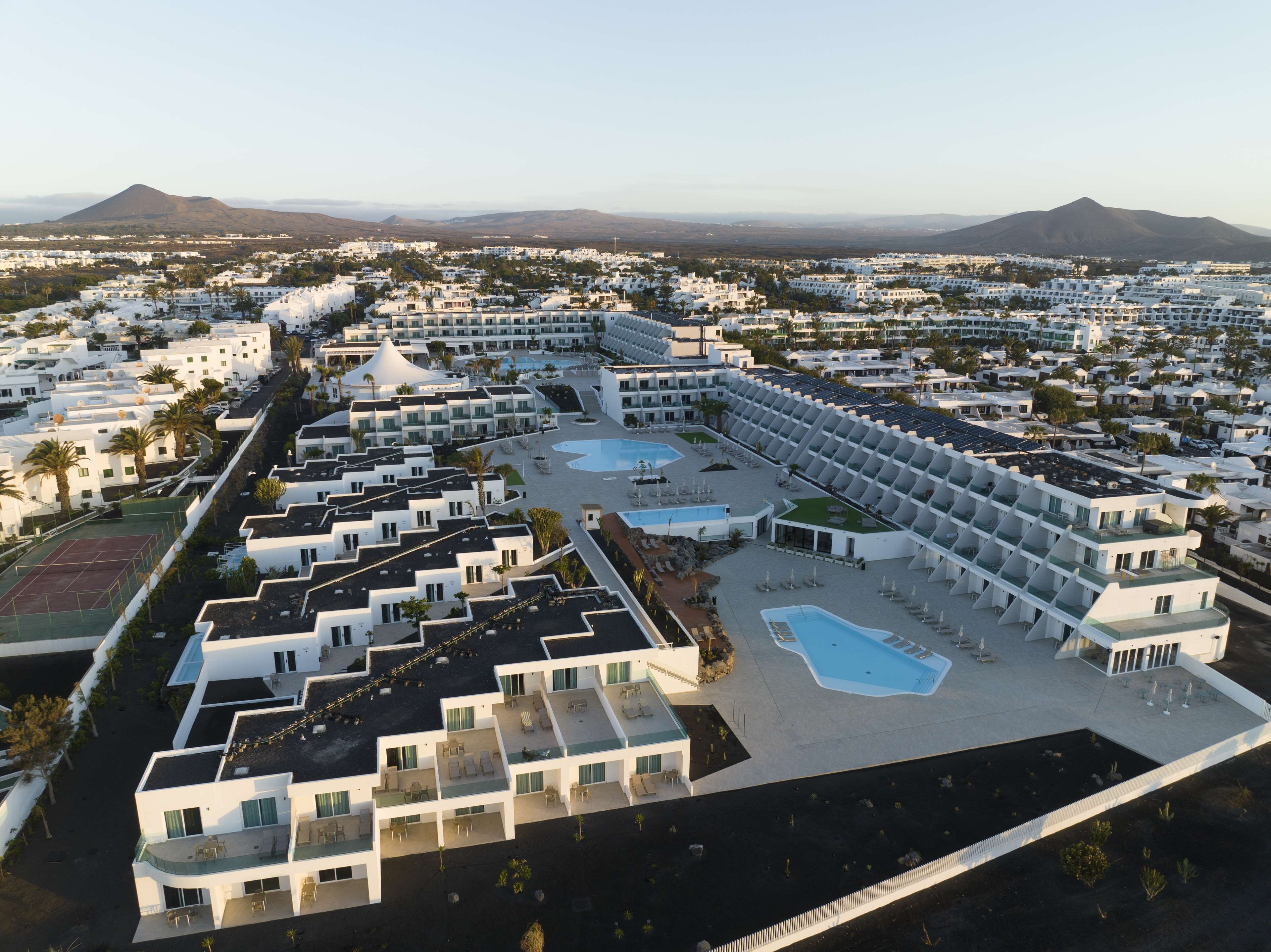 A resort with multiple buildings, a central pool area, and a mountainous backdrop.