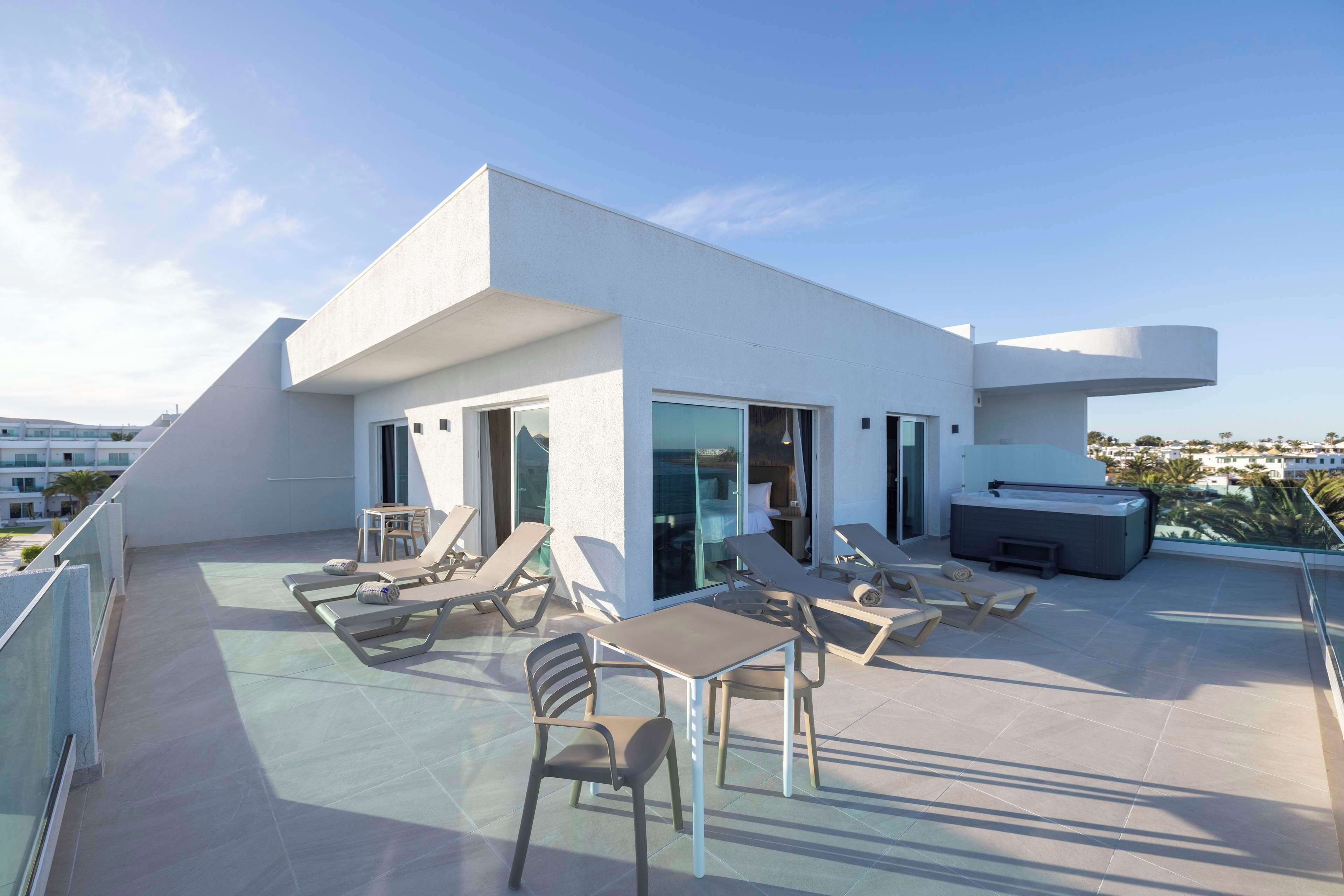 A modern rooftop terrace with lounge chairs, a table, and a sofa.