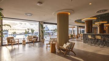 Un vestíbulo espacioso con vista a la piscina, muebles de madera y un pilar central.