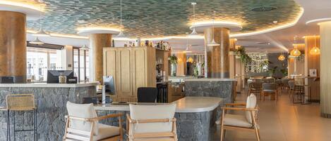 A modern hotel lobby with a curved ceiling, stone bar counter, and wooden chairs.