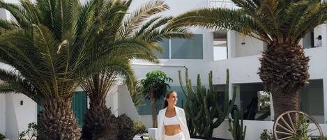 A modern building with a white exterior, palm trees, and a large wheel structure.