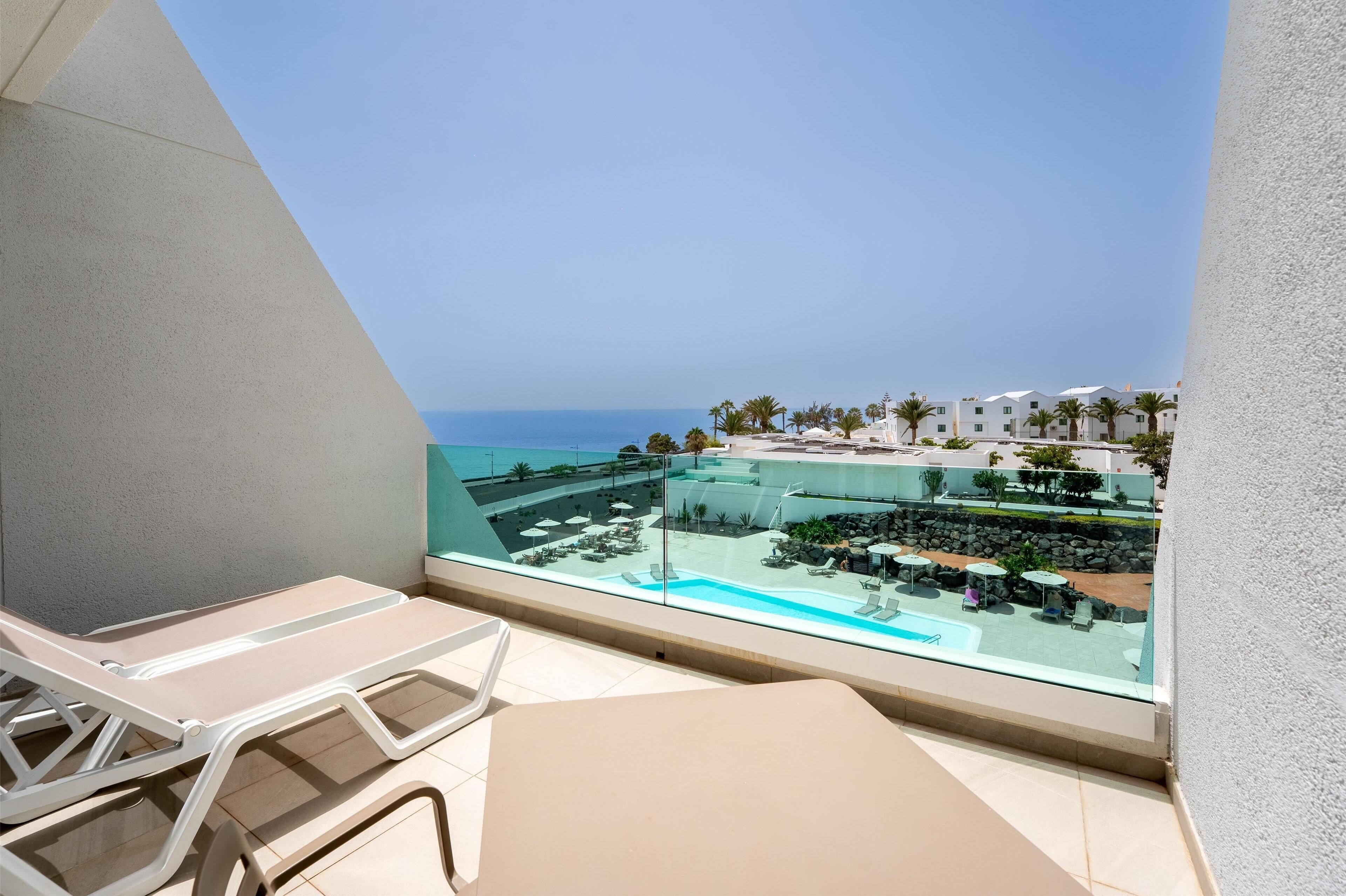 A balcony with a view of a pool and resort buildings.