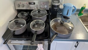 A kitchen with a stove, pots, a coffee maker, and a blue mug.