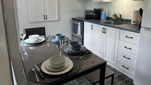 A modern kitchen with white cabinets, a black countertop, and a dining table set with plates, bowls, and cutlery.