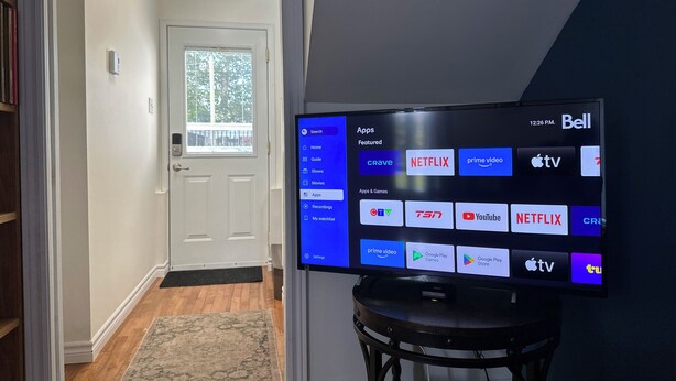 A flat-screen TV mounted on a wall displaying a home screen with various app icons.