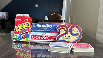 Una mesa con juegos de UNO, Skip-Bone y Monopoly, junto con algunas cartas.