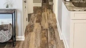 Un pasillo con piso de madera, un lavamanos, armarios y un televisor en la pared.