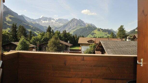 A wooden cabin with a view of mountains and a small village. - Am Liimerweg by Interhome (Adelboden)