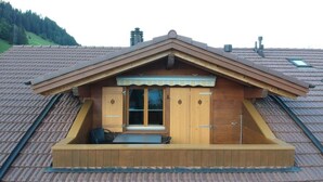 A chalet with a dormer window, wooden exterior, and a small balcony with a table and chairs. - Am Liimerweg by Interhome (Adelboden)