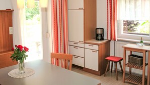 A compact kitchen with a dining table, chairs, a coffee maker, and a window with curtains. - Apartment Frieda by Interhome (Landeck)