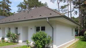 A single-story building with a tiled roof, a front porch, and a small garden area with various plants and flowers. - Vacation home Enikö by Interhome (Ostseebad Lubmin)