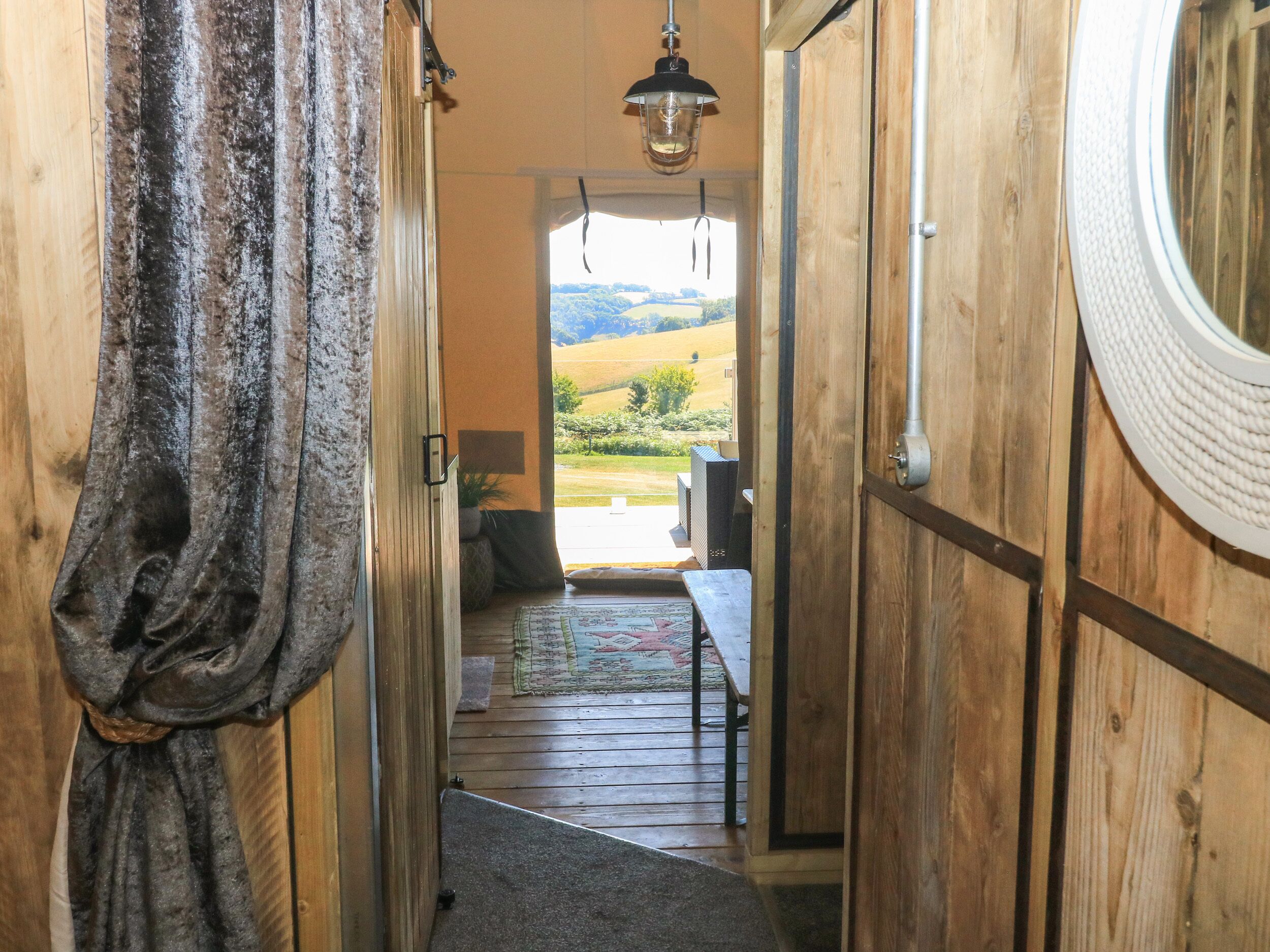 Ein heller, holzgetäfelter Gang führt zu einem Balkon mit Blick auf die Landschaft.