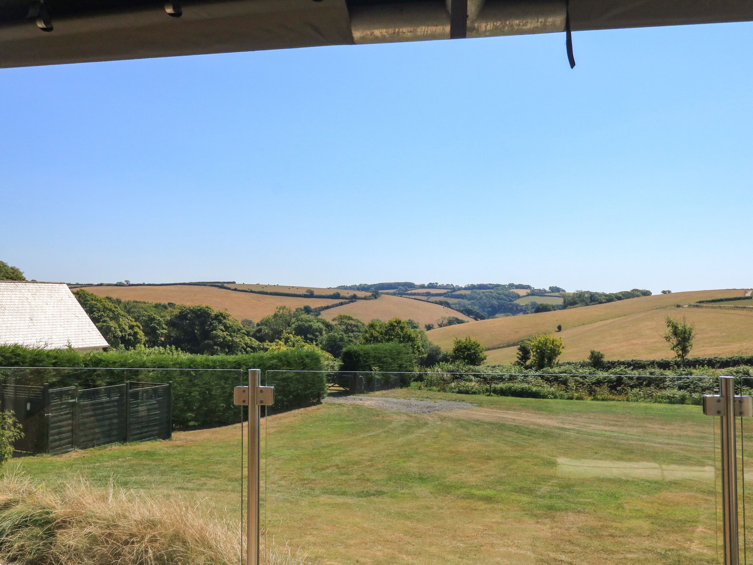 A rural landscape with rolling hills, a fenced area, and a clear sky.