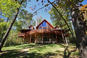 A cabin with a large porch, multiple windows, and a chimney.