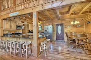 Interior de una cabaña de madera con cocina, barra y comedor.