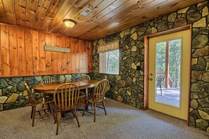 A wooden-paneled room with a stone wall and a door leading outside.