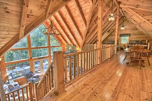 A wooden cabin with a high ceiling, a dining area, and a balcony with a view of the surrounding forest. - Hidden Valley Lodge, 8-BedRm Lodge - Hocking Hills (Logan)