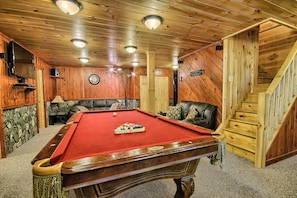 Un interior de madera con mesa de billar, asientos de cuero y una escalera.