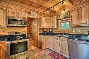 A wooden cabin-style kitchen with a stove, oven, microwave, and coffee maker.
