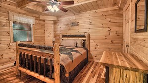A wooden cabin bedroom with a bed, a nightstand, a ceiling fan, and a window with blinds. - Maple Ridge Lodge - 5-Bedroom Lodge -Hocking Hills (South Bloomingville)