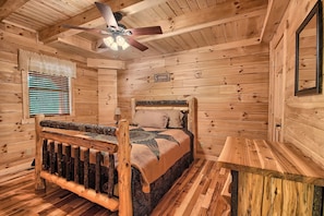 A wooden cabin bedroom with a bed, a wooden bench, a ceiling fan, and a window with blinds. - Maple Ridge Lodge - 5-Bedroom Lodge -Hocking Hills (South Bloomingville)