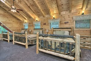 A cabin with three wooden beds, each with a unique design, and a ceiling fan. - Maple Ridge Lodge - 5-Bedroom Lodge -Hocking Hills (South Bloomingville)