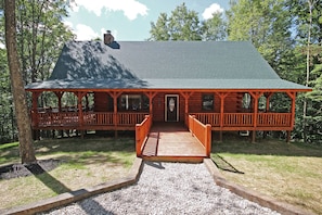 A wooden cabin with a porch, a covered deck, and a gravel pathway leading to the entrance. - Maple Ridge Lodge - 5-Bedroom Lodge -Hocking Hills (South Bloomingville)