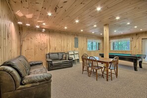 A cozy room with wooden walls, a pool table, a leather sofa, and a dining table with chairs. - Maple Ridge Lodge - 5-Bedroom Lodge -Hocking Hills (South Bloomingville)