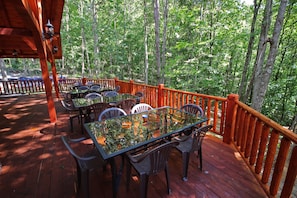 A wooden deck with outdoor seating and a view of a forest.