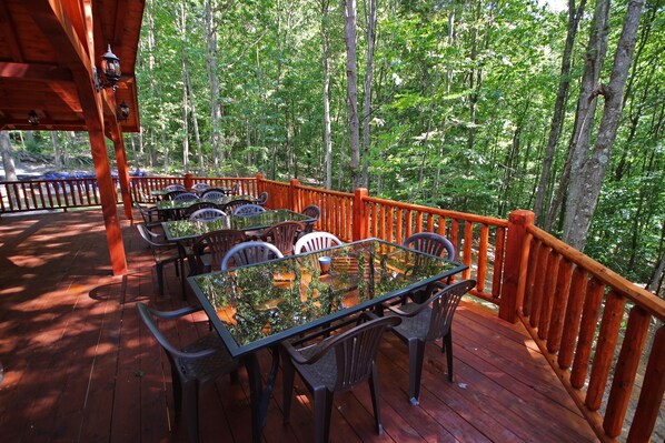 A wooden deck with outdoor seating and a view of a forest. - Maple Ridge Lodge - 5-Bedroom Lodge -Hocking Hills (South Bloomingville)