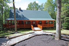 A wooden cabin with a porch and a covered deck, surrounded by trees. - Maple Ridge Lodge - 5-Bedroom Lodge -Hocking Hills (South Bloomingville)