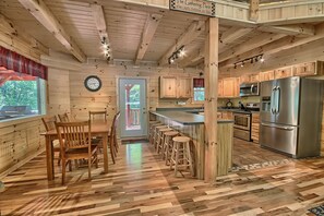 Une cuisine de style rustique, avec des murs en bois, un coin repas, un plancher en bois et un comptoir-bar.