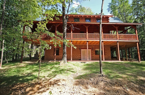 A wooden cabin with a balcony, surrounded by trees. - Maple Ridge Lodge - 5-Bedroom Lodge -Hocking Hills (South Bloomingville)