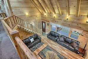 A wooden interior with a staircase, two leather sofas, and a wooden ceiling.