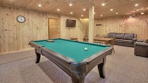A pool table in a room with wooden walls and ceiling, a clock, and a television. - Maple Ridge Lodge - 5-Bedroom Lodge -Hocking Hills (South Bloomingville)