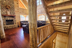 A wooden interior with a stone fireplace, a leather sofa, and a wooden staircase. - Dogwood Lane Lodge- sleeps up to 18 -Hocking Hills (Logan)